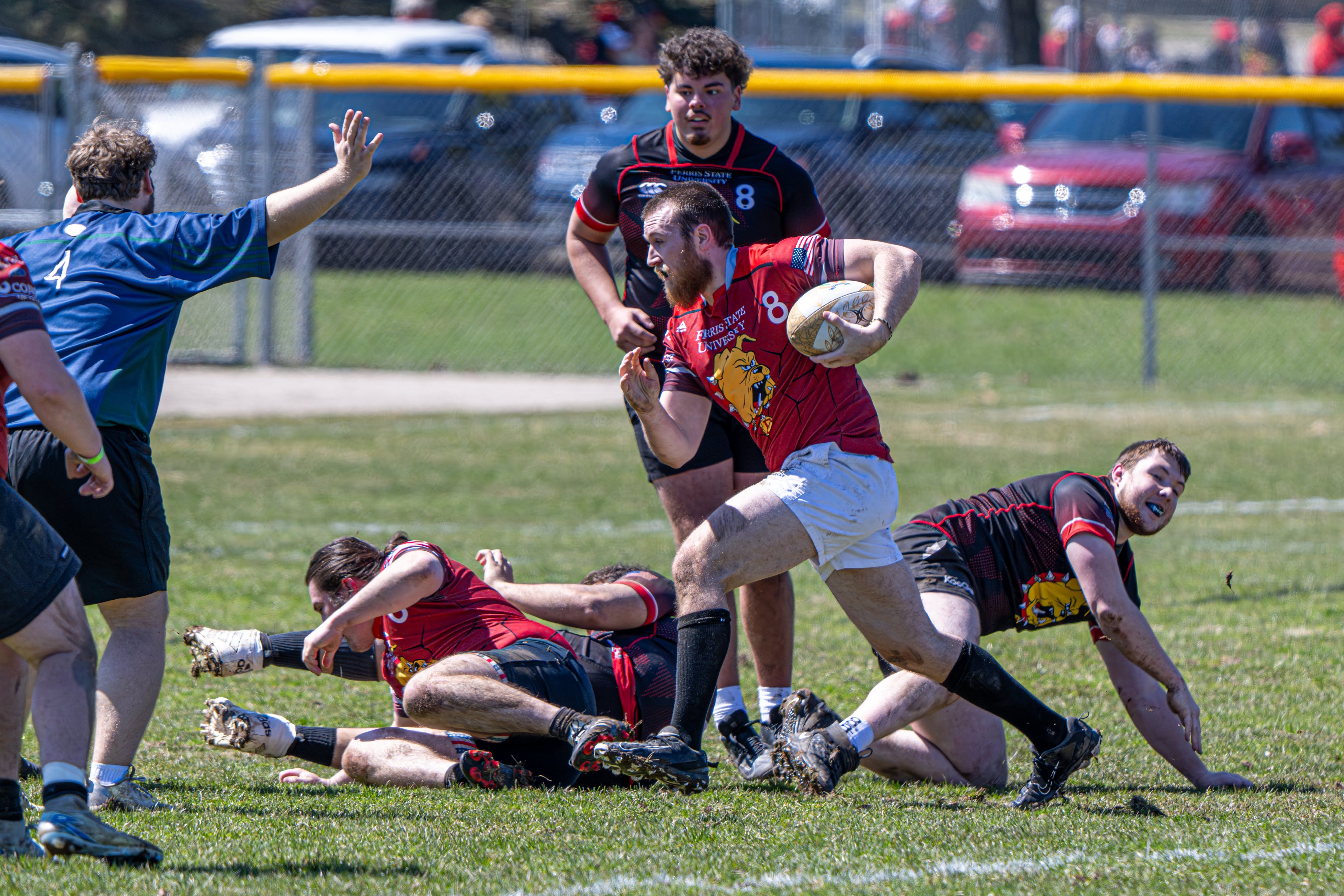 Ferris State rugby player charging forward with the ball as teammates support him